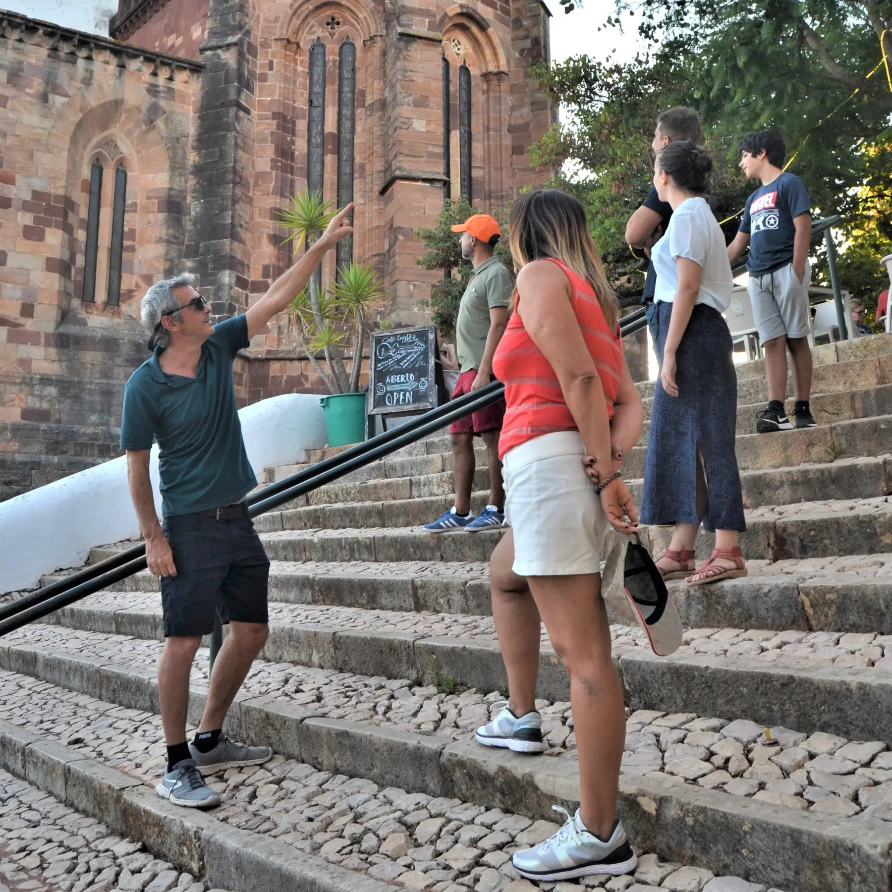 Thyl pointing out details of a red-stone church to a walking group