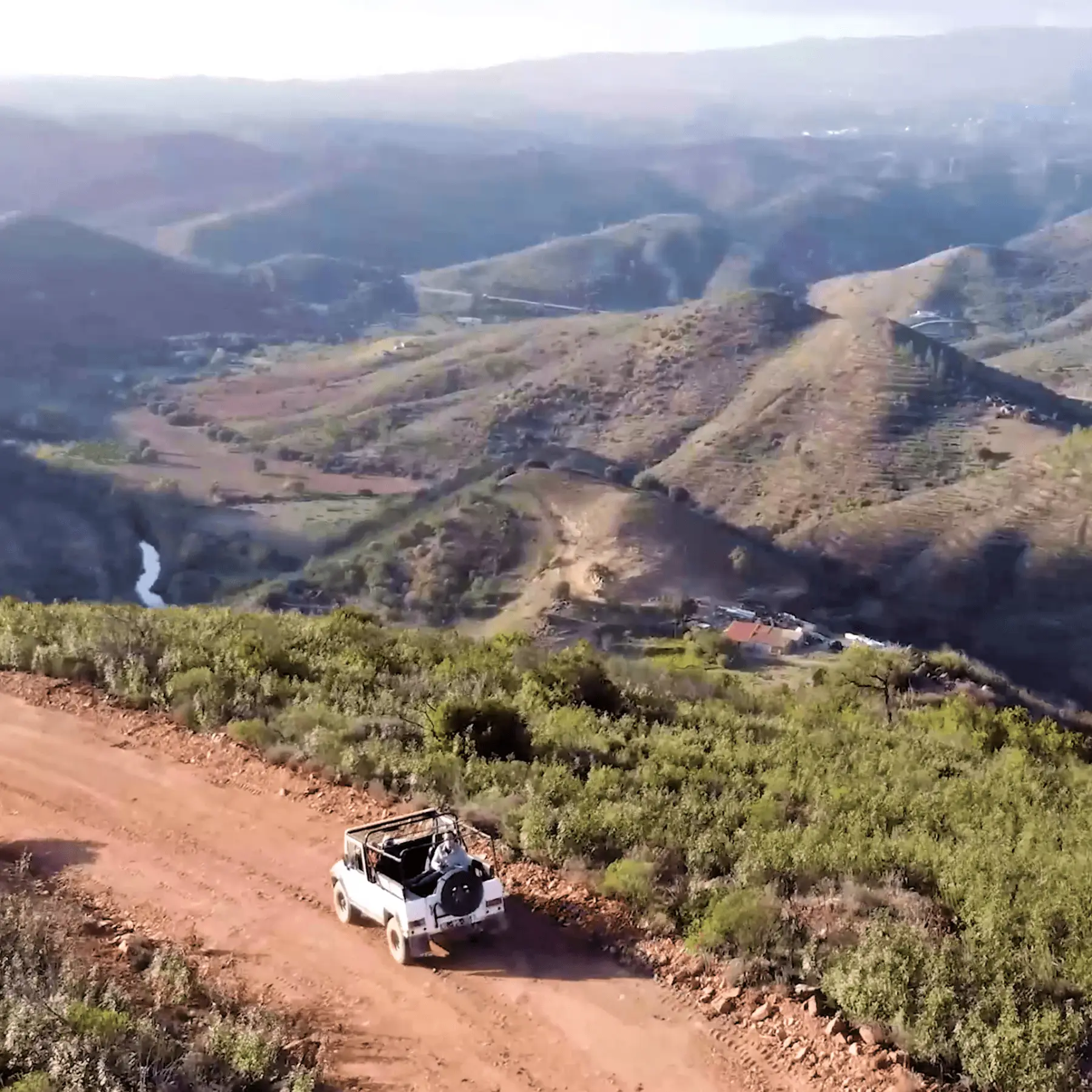 White open jeep following a rough hill track